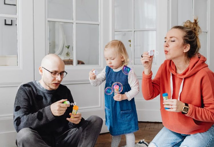 Family enjoying quality time blowing bubbles indoors, capturing joyful moments.